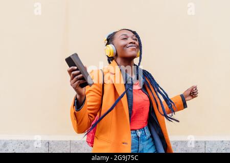 Italia, Milano, Donna con cuffie e smartphone ballano all'aperto Foto Stock