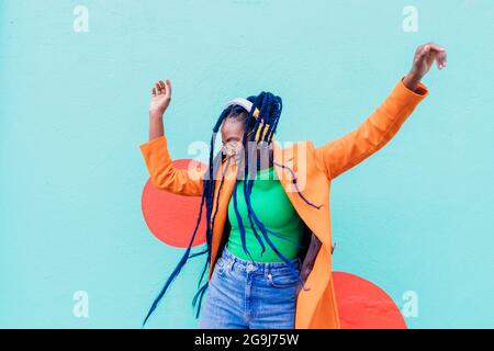 Italia, Milano, donna elegante con cuffie che ballano contro il muro Foto Stock