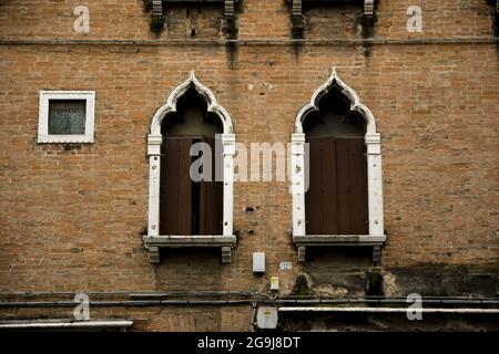 Primo piano di belle finestre architettoniche su una parete di mattoni lungo il canale di Venezia Foto Stock
