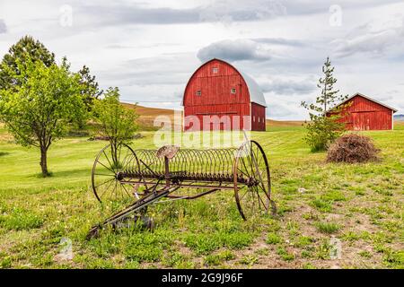 Albion, Washington, Stati Uniti. 23 maggio 2021. Granai rossi e attrezzature antiche nelle colline di Palouse. Foto Stock