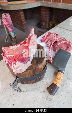 Carne cruda su un ponte, un coltello bloccato nella carne. Carne fresca su un tagliere. Primo piano. Foto Stock