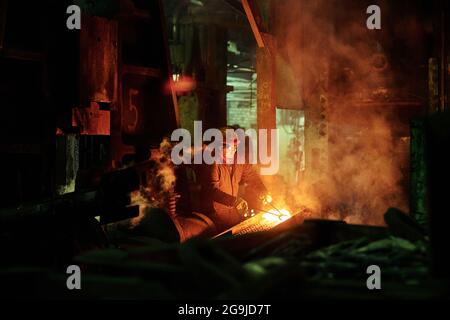 Lavoratore in indumenti da lavoro protettivi che opera presso l'impianto metallurgico Foto Stock