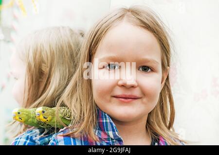 bambina con pappagallo ondulato sulla spalla Foto Stock