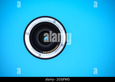 Obiettivo di una telecamera mirrorless full-frame; montaggio con contatti elettrici per i dati dell'obiettivo; sfondo blu e spazio di copia Foto Stock