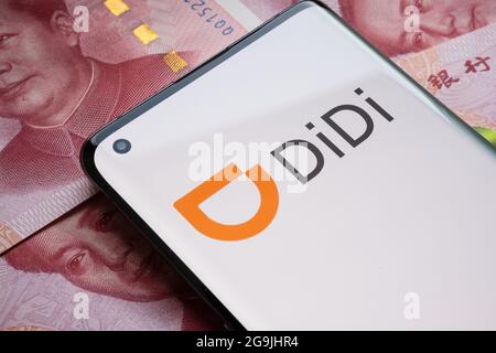 Didi Chuxing Technology logo della società visto su smartphone collocato su 100 yuan banconote. Concetto. Stafford, Regno Unito, 26 luglio 2021. Foto Stock