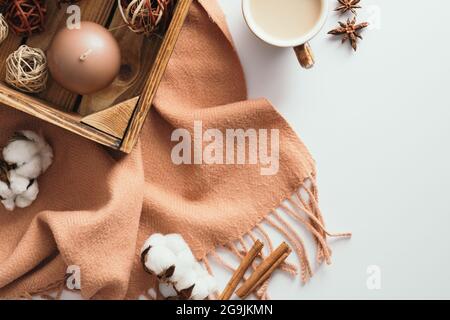Accogliente tavolo da scrivania con plaid marrone, caffettiera, candela, cotone su sfondo bianco. Vista dall'alto, disposizione piatta. Composizione autunnale. Conc. Stile igge nordico Foto Stock