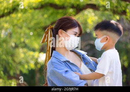 madre giovane e figlio che indossano maschere chirurgiche per la protezione durante la quarantena Foto Stock