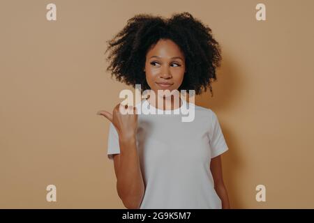 Bella donna africana capelli ricci punta pollice da parte, raccomanda promo e pubblicizza il prodotto Foto Stock