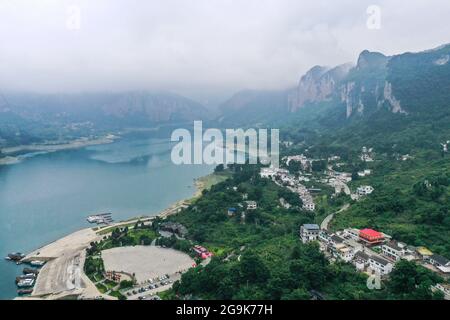 (210726) -- QIANXI, 26 luglio 2021 (Xinhua) -- Foto aerea scattata il 24 luglio 2021 mostra una vista del villaggio di Huawu a Xinren Miao Township, Qianxi City, provincia di Guizhou, nella Cina sudoccidentale. Huawu Village, pur vantando una cultura etnica Miao unica e splendide viste sulle montagne con vasti corpi idrici, una volta aveva un rapporto di povertà fino al 63.6%. Approfittando del ricco patrimonio culturale e naturale, il governo locale ha avviato un progetto di area panoramica come misura mirata per scuotere la povertà per stimolare il turismo, costruendo una "galleria lunga delle persone" . Il villaggio che una volta h Foto Stock