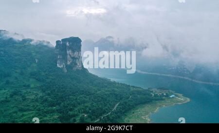 (210726) -- QIANXI, 26 luglio 2021 (Xinhua) -- Foto aerea scattata il 24 luglio 2021 mostra una vista di prima mattina del villaggio di Huawu nella cittadina di Xinren Miao, Qianxi City, provincia di Guizhou, nella Cina sudoccidentale. Huawu Village, pur vantando una cultura etnica Miao unica e splendide viste sulle montagne con vasti corpi idrici, una volta aveva un rapporto di povertà fino al 63.6%. Approfittando del ricco patrimonio culturale e naturale, il governo locale ha avviato un progetto di area panoramica come misura mirata per scuotere la povertà per stimolare il turismo, costruendo una "galleria lunga delle persone" . Il vill Foto Stock