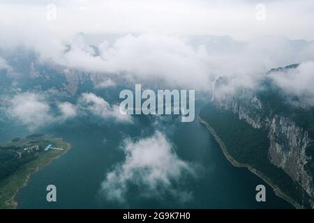 (210726) -- QIANXI, 26 luglio 2021 (Xinhua) -- Foto aerea scattata il 24 luglio 2021 mostra una vista di prima mattina del villaggio di Huawu nella cittadina di Xinren Miao, Qianxi City, provincia di Guizhou, nella Cina sudoccidentale. Huawu Village, pur vantando una cultura etnica Miao unica e splendide viste sulle montagne con vasti corpi idrici, una volta aveva un rapporto di povertà fino al 63.6%. Approfittando del ricco patrimonio culturale e naturale, il governo locale ha avviato un progetto di area panoramica come misura mirata per scuotere la povertà per stimolare il turismo, costruendo una "galleria lunga delle persone" . Il vill Foto Stock