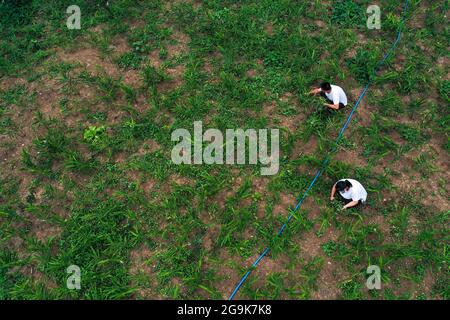 (210726) -- QIANXI, 26 luglio 2021 (Xinhua) -- Villaggio cadre ai Xing (in alto) e sua moglie erbaccia nel campo a Huawu Village a Xinren Miao Township, Qianxi City, Provincia di Guizhou, 24 luglio 2021. Huawu Village, pur vantando una cultura etnica Miao unica e splendide viste sulle montagne con vasti corpi idrici, una volta aveva un rapporto di povertà fino al 63.6%. Approfittando del ricco patrimonio culturale e naturale, il governo locale ha avviato un progetto di area panoramica come misura mirata per scuotere la povertà per stimolare il turismo, costruendo una "galleria lunga delle persone" . Foto Stock