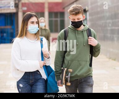 Adolescenti in maschere a piedi dopo le lezioni Foto Stock