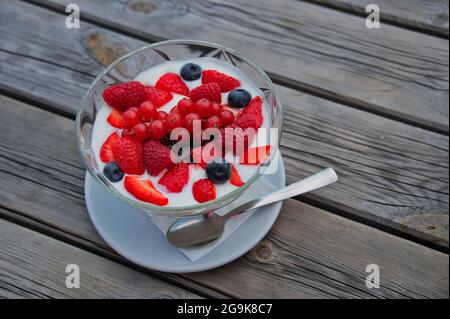 Ciotola con frutti di bosco freschi su tavolo di legno Foto Stock