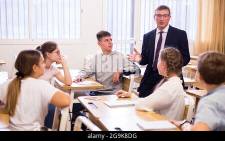 Insegnante positivo con studenti adolescenti durante la lezione Foto Stock