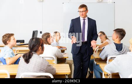 Insegnante positivo con studenti adolescenti durante la lezione Foto Stock