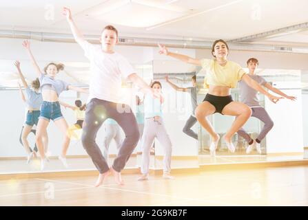 Gruppo di giovani ballerini che saltano insieme in classe Foto Stock