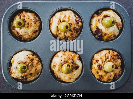 focaccia vegana muffin saporiti con pomodori secchi e olive nel vassoio appena fuori dal forno, salutari ricette a base di piante Foto Stock