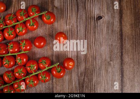 Capriate di piccoli pomodori ciliegini su fondo di legno con spazio di copia Foto Stock