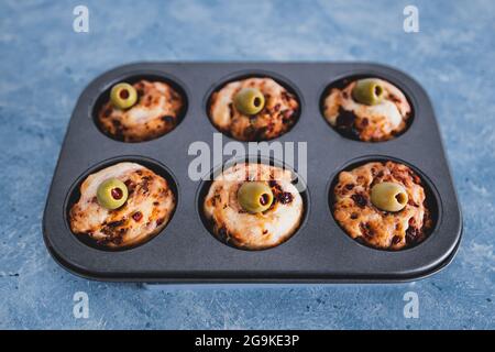 focaccia vegana muffin saporiti con pomodori secchi e olive nel vassoio appena fuori dal forno, salutari ricette a base di piante Foto Stock