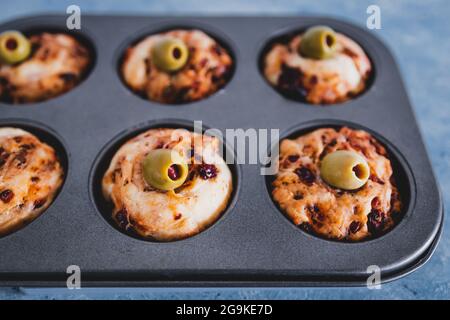 focaccia vegana muffin saporiti con pomodori secchi e olive nel vassoio appena fuori dal forno, salutari ricette a base di piante Foto Stock