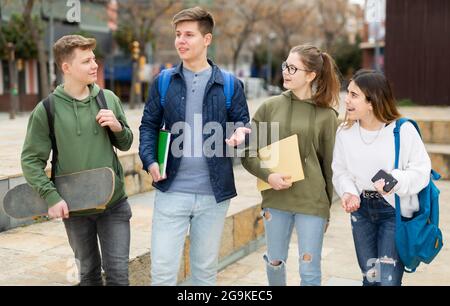 Gli studenti che camminano fuori dalla scuola sono spensierati Foto Stock