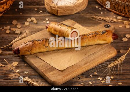 Panino lungo fatto in casa farcito con salsiccia su sfondo di legno Foto Stock