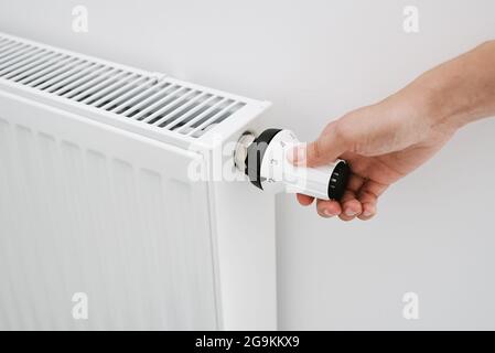 Riscaldare la manopola del radiatore. Donna regolazione manuale della temperatura sul radiatore di riscaldamento Foto Stock
