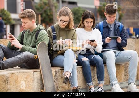 Gruppo di ragazzi che utilizzano gli smartphone all'aperto Foto Stock