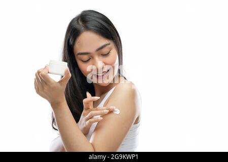 donna asiatica che indossa un vestito bianco con crema per il corpo strofinare nel braccio Foto Stock