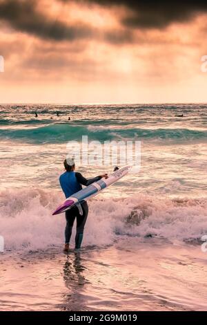 Luce in tarda serata su un membro del Newquay Surf Lifesaving Club durante una sessione di allenamento a Fistral Beach a Newquay in Cornovaglia. Foto Stock