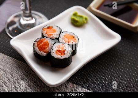 Sushi maki di salmone fresco servito su piatto bianco con wasabi e salsa di soia Foto Stock