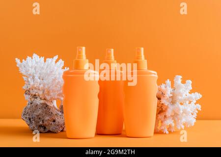 contenitori con protezione solare vicino ai coralli marini isolati su arancione Foto Stock