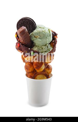 Cialde di Hong Kong con gelato al pistacchio decorato con piatti e cioccolato in tazza di carta isolato su sfondo bianco. Waffle a bolle d'aria, waffle, pennsylvania Foto Stock