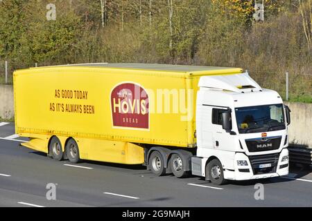 Vista frontale distribuzione del pane hgv catena di fornitura alimentare camion bianco e cabina conducente Hovis pubblicità sul lato del rimorchio giallo guida su autostrada UK Foto Stock