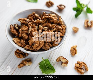 Noci senza guscio su fondo bianco di legno Foto Stock