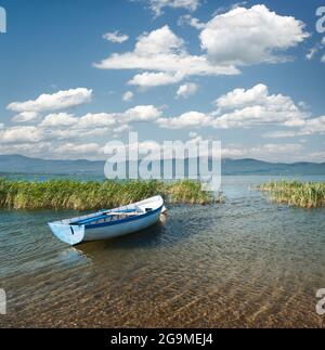 Vista di una barca a remi e cloudscape sul lago Prespa dal lato macedone Foto Stock