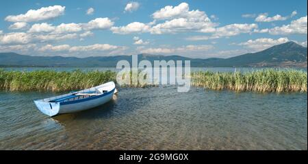 Ampia vista di una barca a remi e di un paesaggio tortuoso sul lago Prespa dal lato macedone Foto Stock