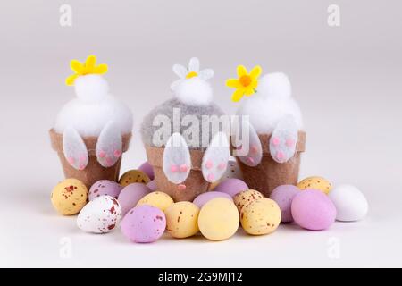 Carino coniglietti di pasqua fury piccolo si imbottisce in su in pentole di fiore con le uova di caramella di cioccolato intorno loro Foto Stock