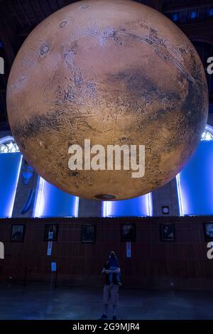 Bristol, Regno Unito. 27 luglio 2021. Luke Jerram mostra il suo modello di Marte di sette metri nella Grande Sala del Wills Memorial Building Bristol University. Utilizzando le immagini della NASA, il modello consente alle persone di vedere le montagne, le valli e i crateri del nostro vicino pianeta Rosso. La mostra sarà aperta al pubblico, al personale e agli studenti dal 27 luglio al 1 agosto. Credit: JMF News/Alamy Live News Foto Stock