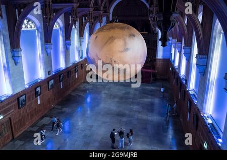 Bristol, Regno Unito. 27 luglio 2021. Luke Jerram mostra il suo modello di Marte di sette metri nella Grande Sala del Wills Memorial Building Bristol University. Utilizzando le immagini della NASA, il modello consente alle persone di vedere le montagne, le valli e i crateri del nostro vicino pianeta Rosso. La mostra sarà aperta al pubblico, al personale e agli studenti dal 27 luglio al 1 agosto. Credit: JMF News/Alamy Live News Foto Stock