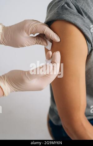 Dose di iniezione di vaccino cosod19 in spalla. Primo piano di un uomo che viene iniettato con il vaccino nella parte superiore del braccio. Foto Stock