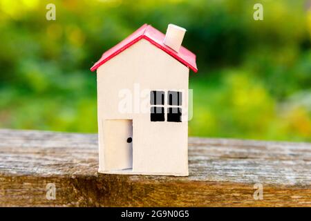 Miniatura bianco giocattolo modello casa su sfondo di legno vicino sfondo verde. Eco Village, astratto contesto ambientale. Ipotecario immobiliare Foto Stock