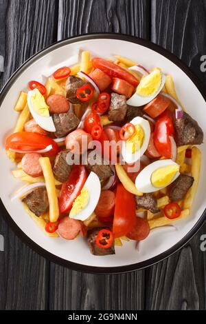 Il pique macho è un piatto molto popolare della Bolivia fatto di tagli di manzo e salsicce fritte con patatine fritte, uova, peperoni e pomodori in primo piano nel piatto Foto Stock