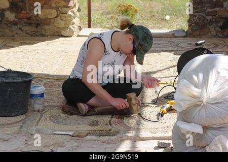 Bitola, Repubblica di Macedonia - 21 luglio 2011: Studente di archeologia, seduto sul pavimento, sta lavorando al restauro dei mosaici dell'episcopale Foto Stock