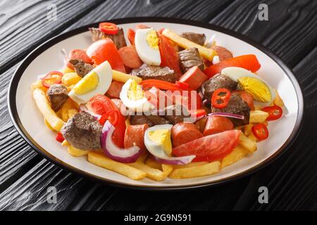 Il gustoso Pique macho è un tipo di gustoso e piccante piatto Boliviano che viene preparato mescolando manzo, salsiccia e verdure al primo piano nel piatto sul tavolo. Hori Foto Stock