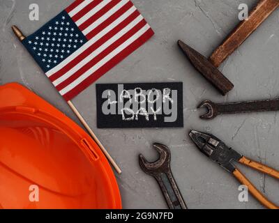 GIORNO DEL LAVORO. Attrezzi manuali e la bandiera degli Stati Uniti d'America che giace sul tavolo. Vista dall'alto, primo piano. Congratulazioni alla famiglia, ai parenti Foto Stock