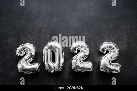 Numeri gonfiabili in argento lucido del nuovo anno 2022 su sfondo grigio scuro o nero. Spazio di copia. Foto Stock