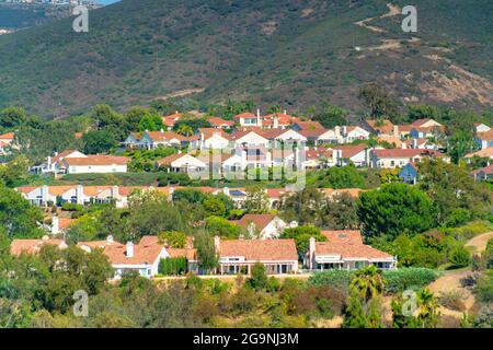 Bella vista di edifici con tetti piastrellati circondato da alberi in una giornata soleggiata estiva Foto Stock