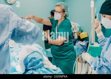 Medici che preparano il paziente in sala operatoria all'ospedale moderno - Focus su infermiere centrale Foto Stock